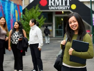 Three residents walking and talking in front of RMIT University building next to Student Living D2.