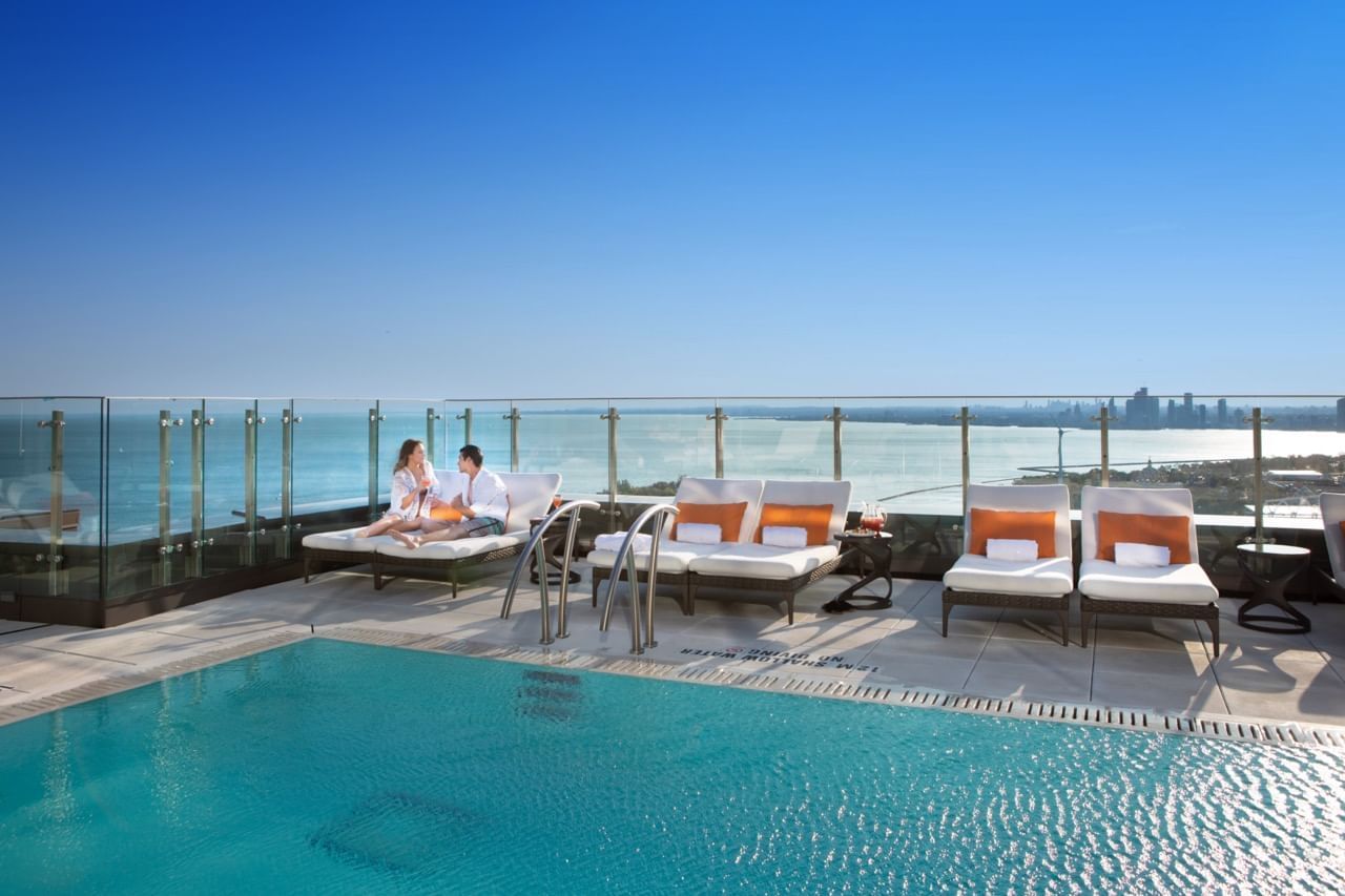 Couple se relaxant au bord de la piscine avec vue sur l'océan à l'hôtel X Toronto