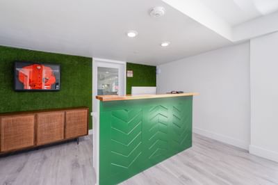 Green moss-wall reception desk with a framed orange jersey at The Varsity South