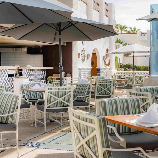 Outdoor dining area in Dos Mares at Marquis Los Cabos Resort with set tables and umbrellas for a relaxing meal