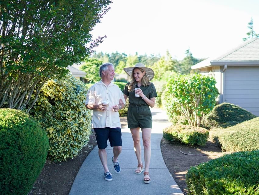 Couple walking on a pathway surrounded by greenery holding coffee cups at Moonstone Hotels.