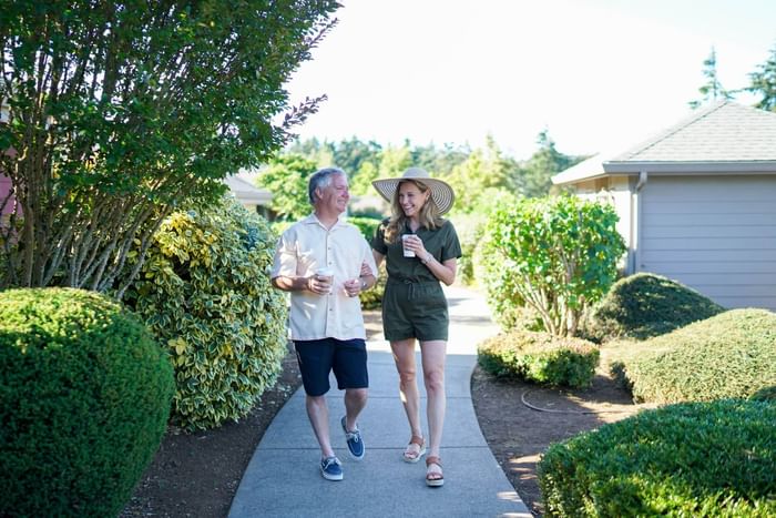 Couple walking on a pathway surrounded by greenery holding coffee cups at Moonstone Hotels.