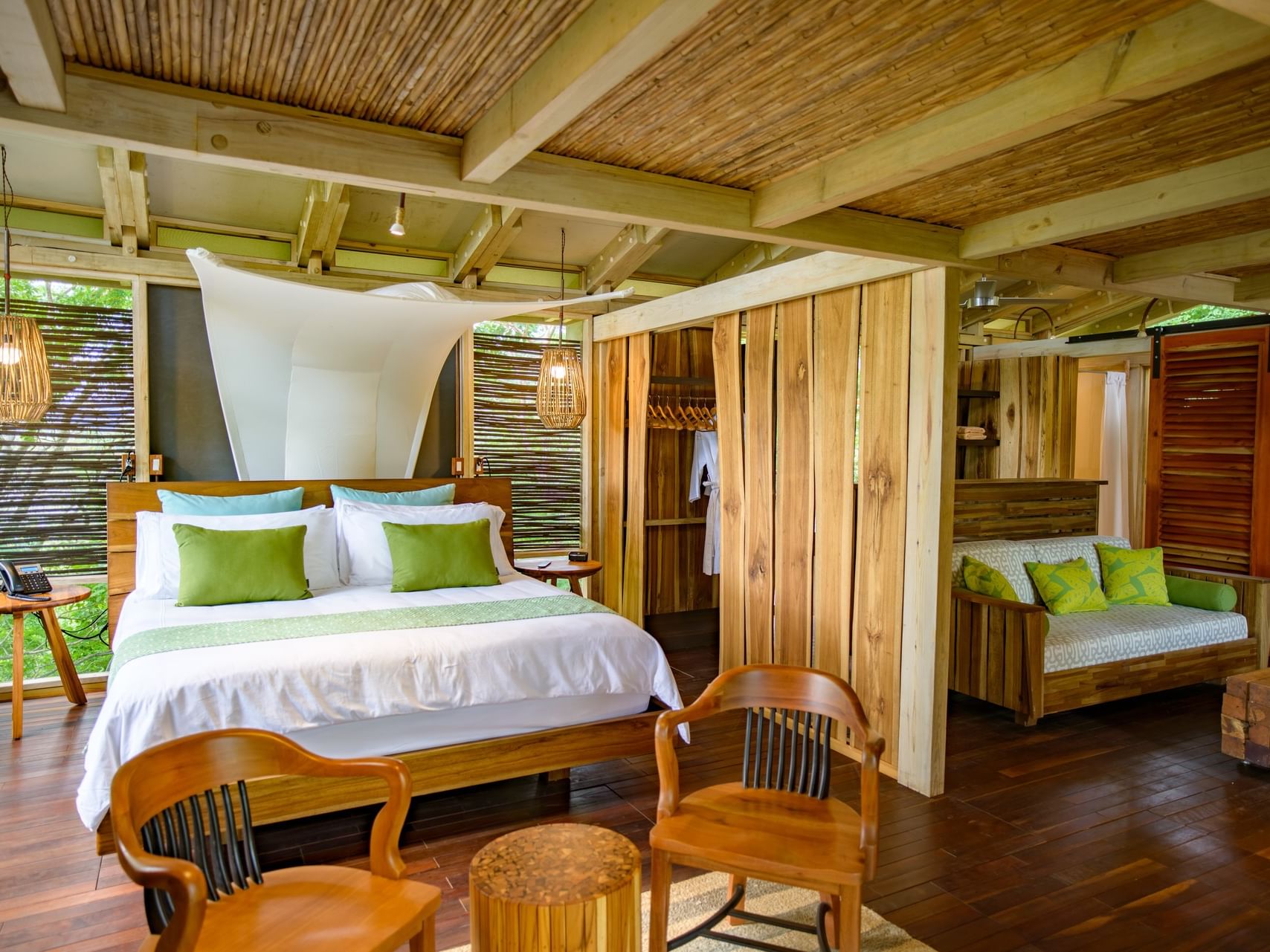 Bed by wood chairs under a bamboo ceiling in Two-bedroom villas with private pool at Morgan's Rock Reserve & Ecolodge