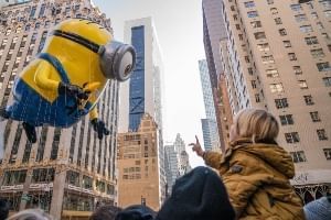A giant minion balloon towering over people watching the Macy's Thanksgiving Day Parade.