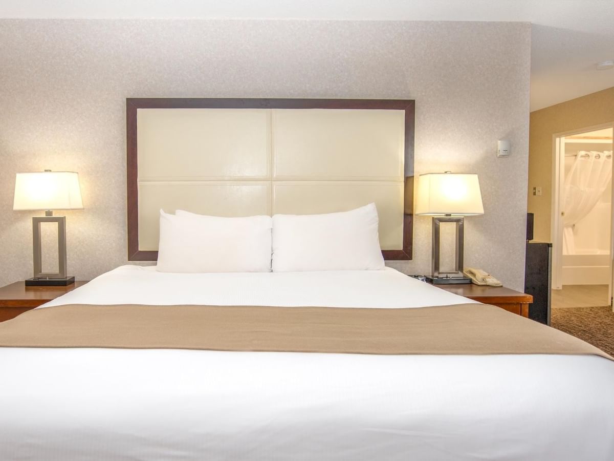 Hotel room with a large bed, two lamps, and a jetted tub.