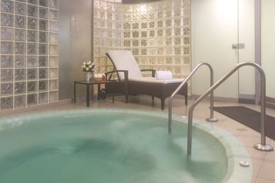 Lounge chair & table with flowers in front of a spa jacuzzi at Hotel Los Delfines & Casino