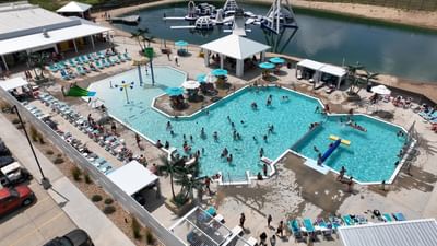 Aerial view of the lively pool area with people, lounge chairs, and the nearby Aqua Park at Off Shore Resort