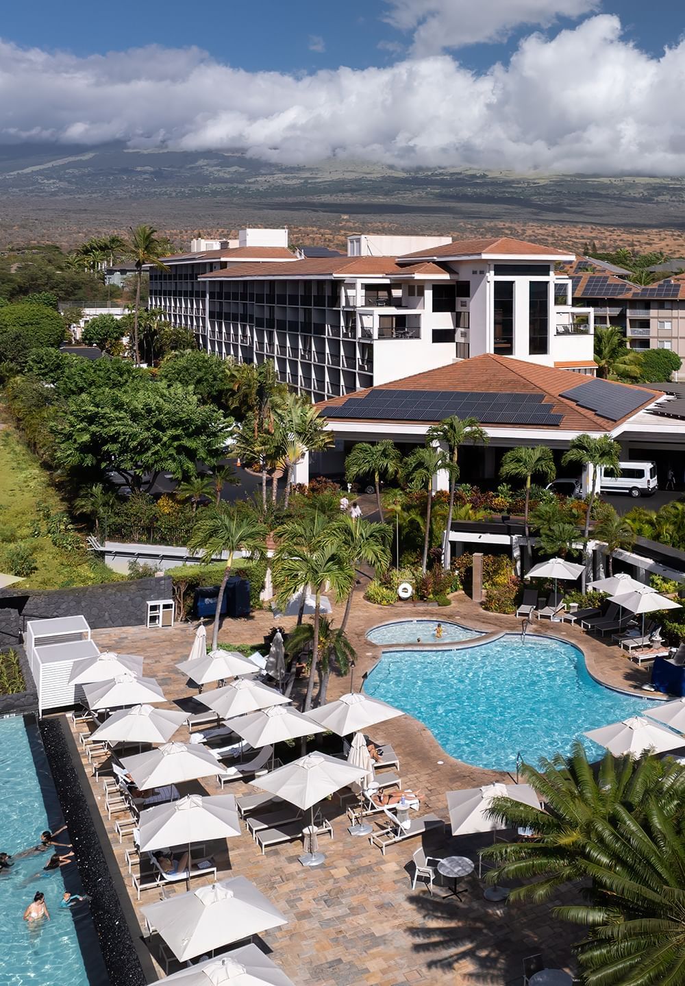 An aerial view of the Maui Coast Hotel showing its pool area with lounge chairs and umbrellas.