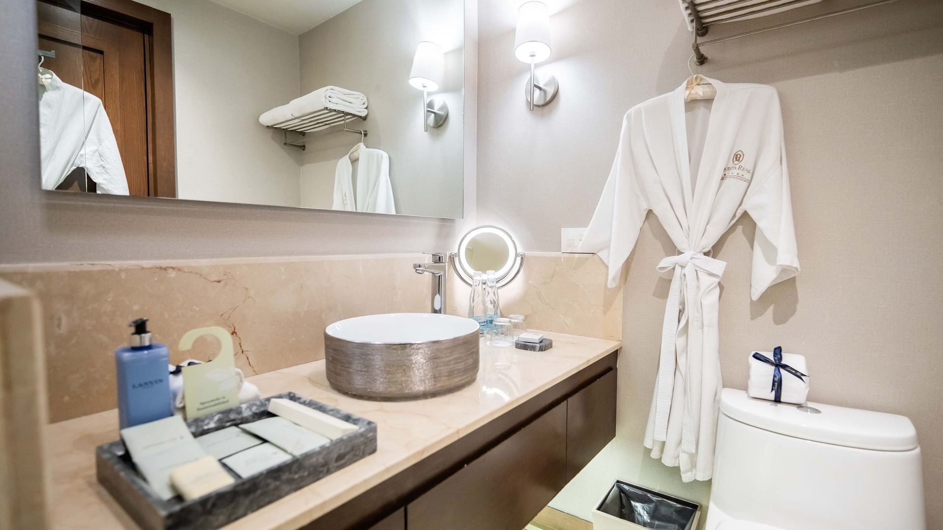 Baño elegante con toallas, espejo grande, lavabo, y bata en la Quinta Real Puebla en Heroica Puebla de Zaragoza