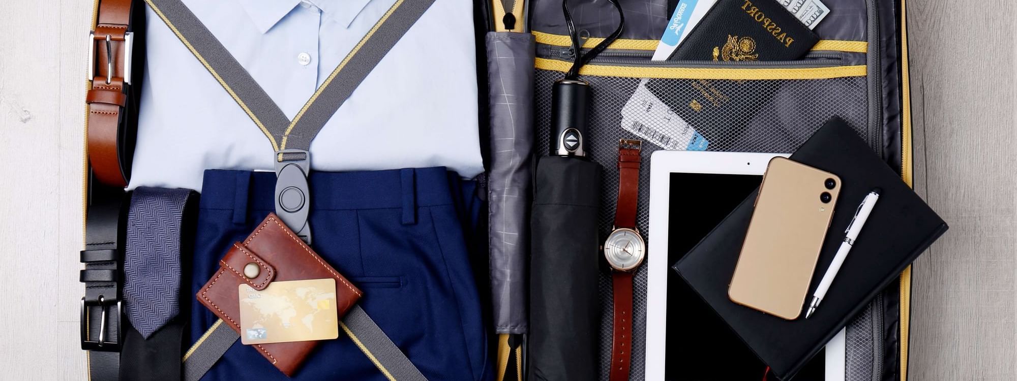 Open suitcase displays packed formal attire, passport, and travel documents at Warwick Melrose Hotel Dallas Ballroom