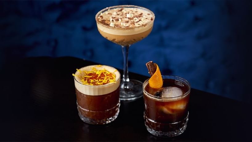 Three cocktails on a black surface against a dark blue background served at Paramount Hotel Dubai