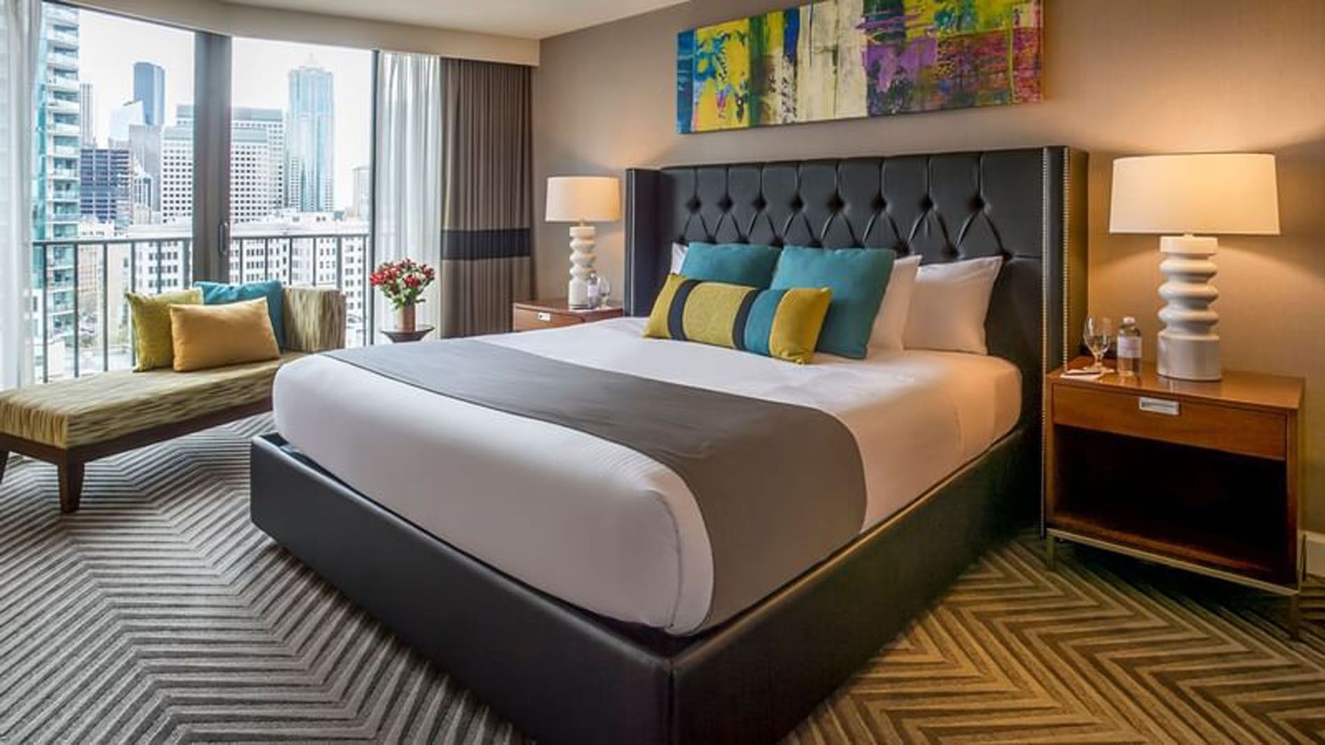 A hotel room with a large bed, city view, and balcony.
