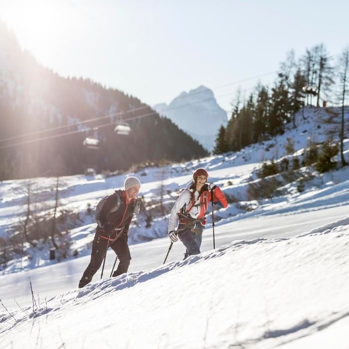 A couple skiing in a snowy land near Falkensteiner Hotels & Residences