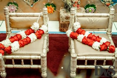 gold chairs with white and red rose necklaces laid on top
