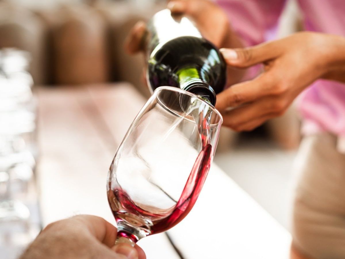 Person pouring red wine into a glass at Grand Fiesta Americana