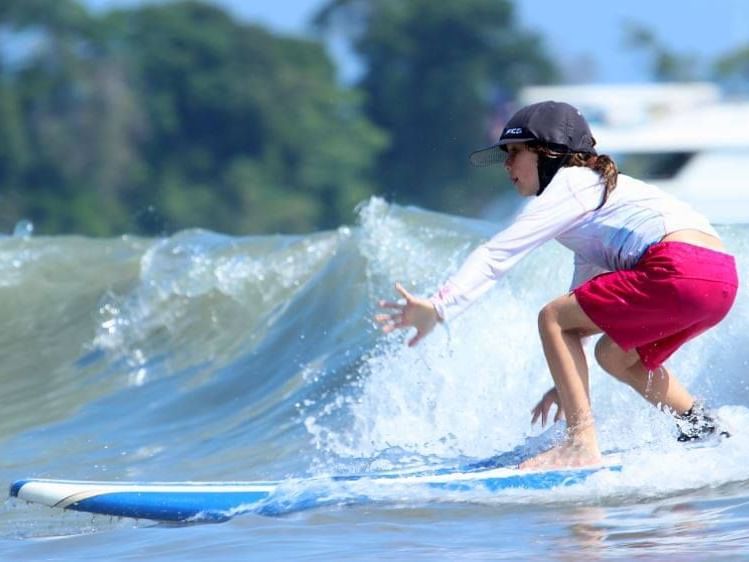 A young girl riding a surfboard on the ocean waves near Los Altos Resort