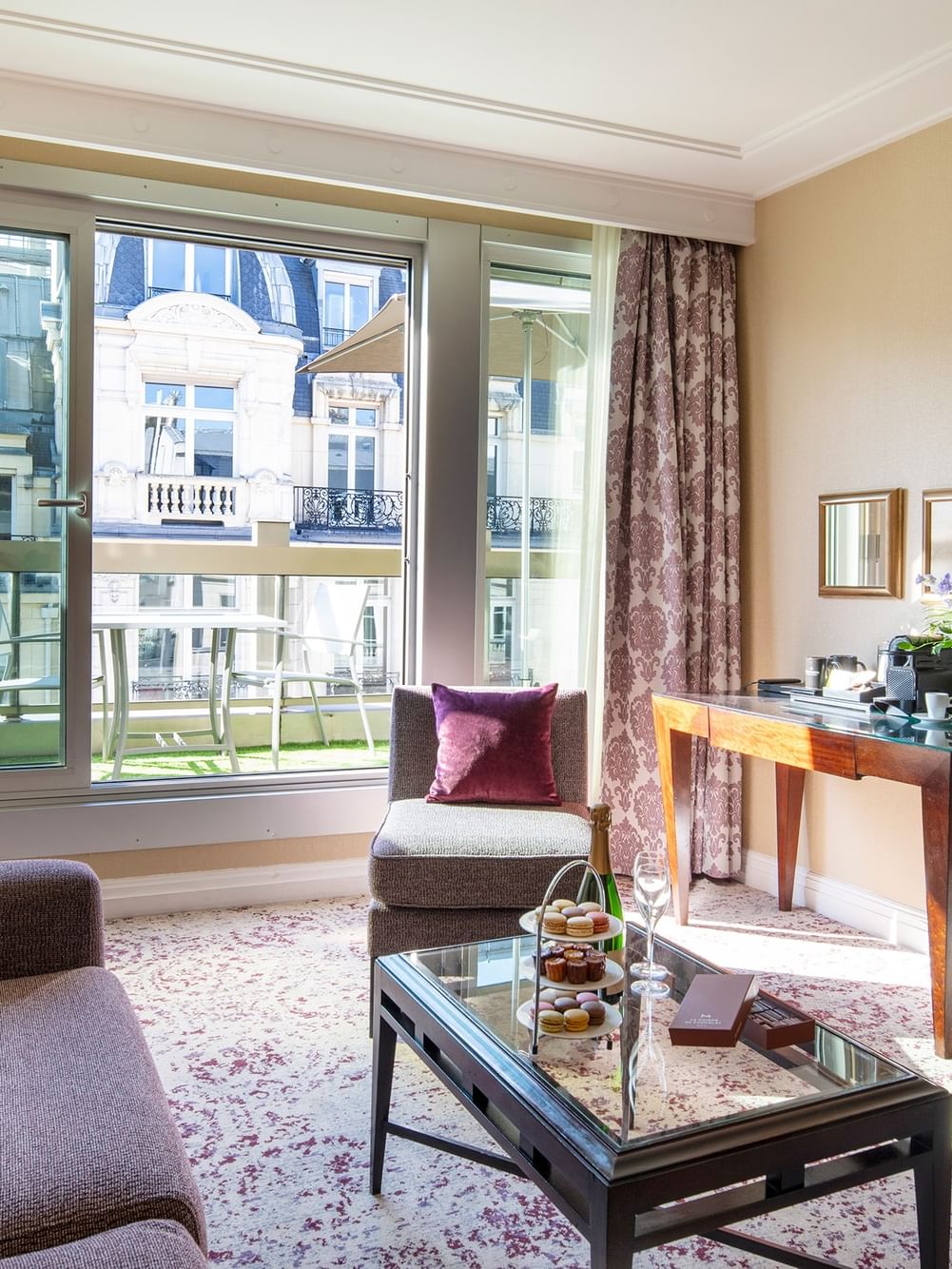 Elegant hotel room with large window, couch, coffee table, and balcony view at Warwick Champs-Elysées Paris.