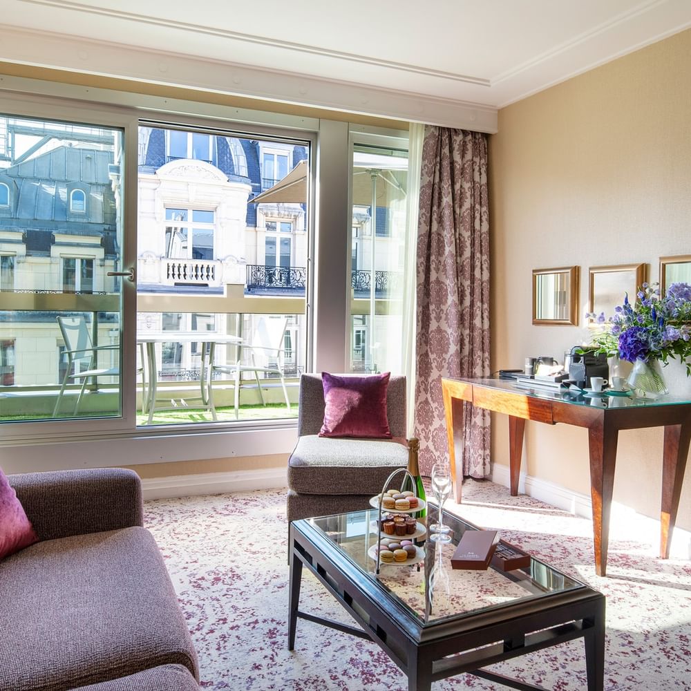 Elegant hotel room with large window, couch, coffee table, and balcony view at Warwick Champs-Elysées Paris