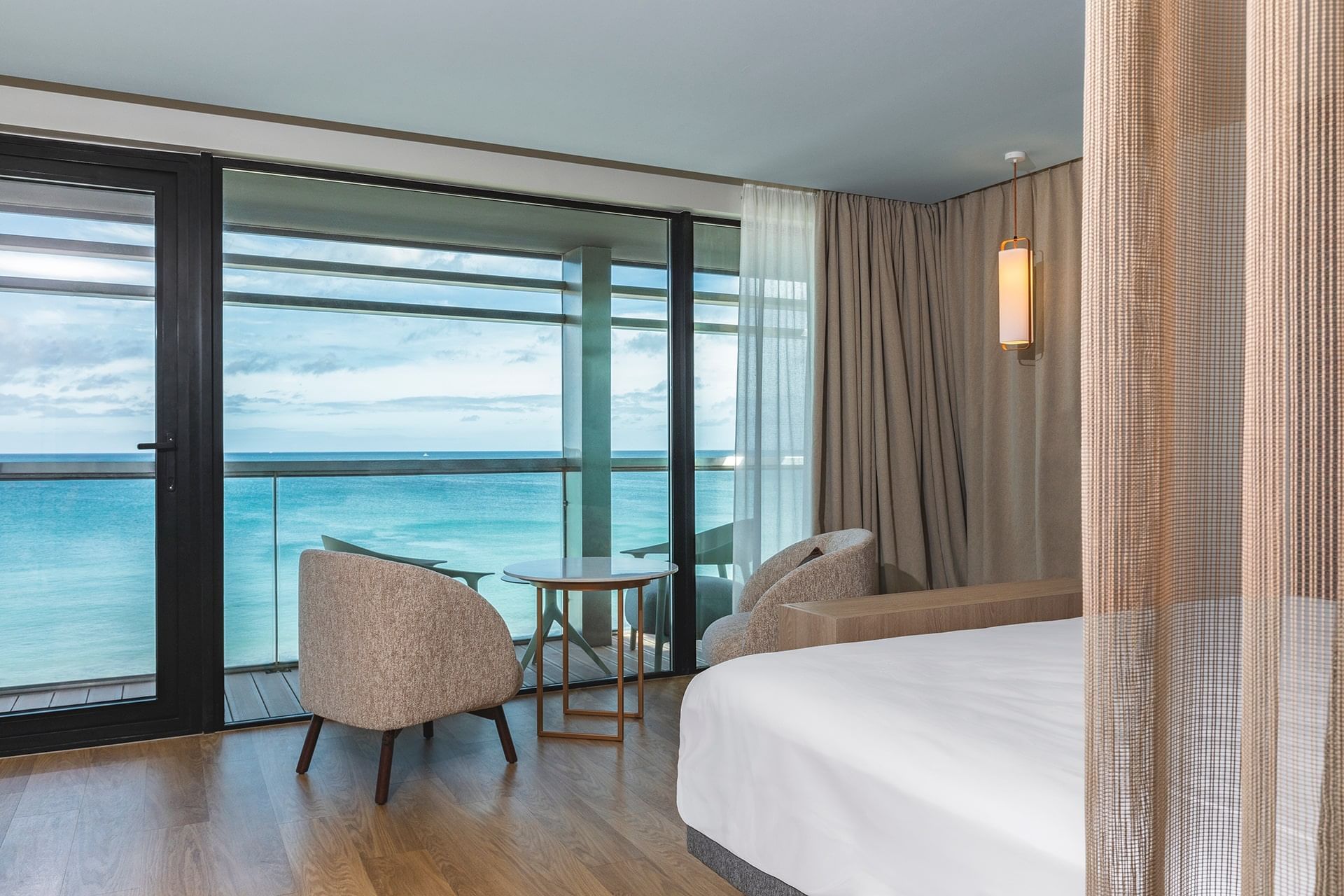 Intérieur et décoration d'un lit king-size avec fauteuils et table basse avec vue sur la mer dans une chambre à l'Oceania Saint-Malo