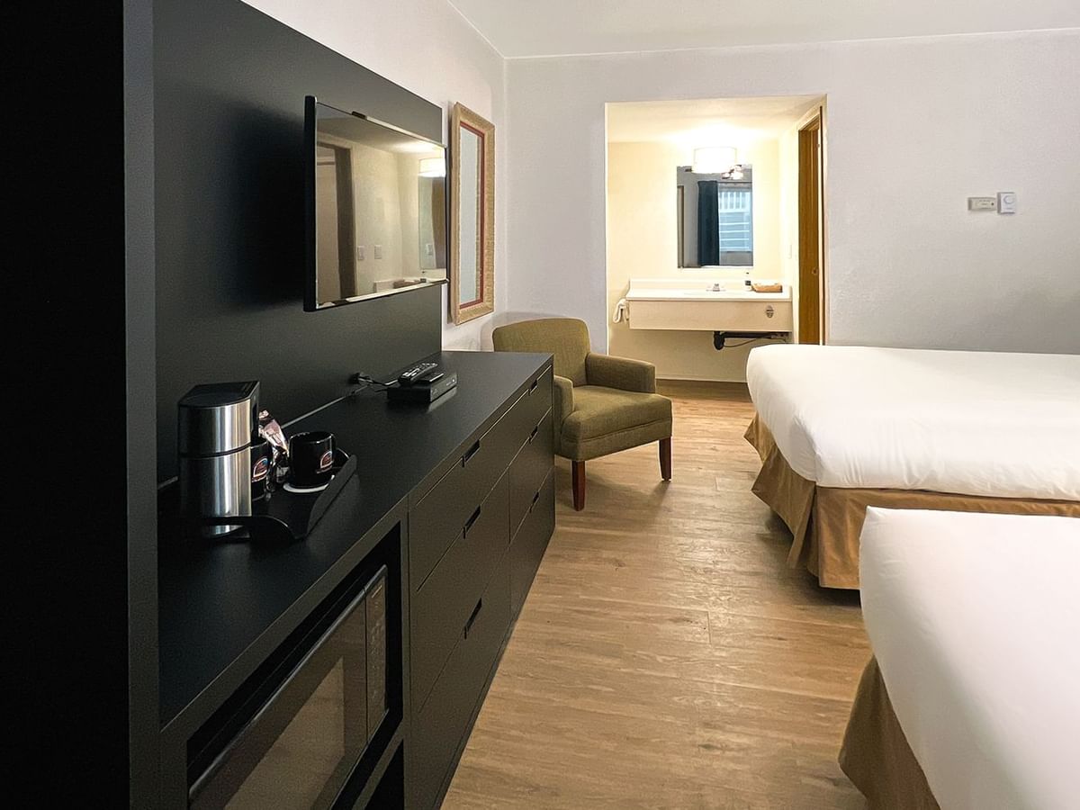 Hotel bedroom with two beds, TV, chair, mirror, microwave, and coffee maker