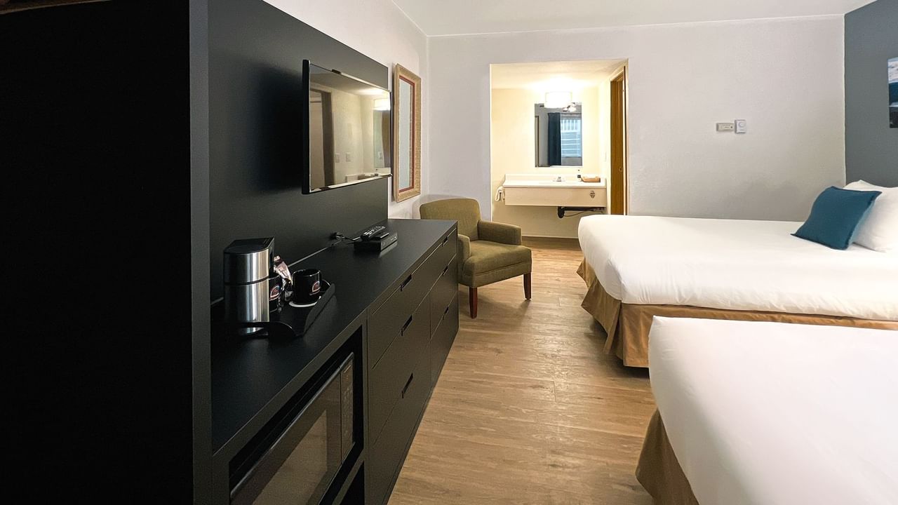 Hotel bedroom with two beds, TV, chair, mirror, microwave, and coffee maker