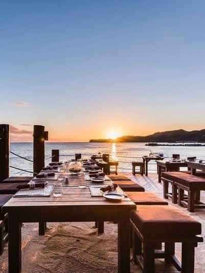 Long wooden tables with benches by a rope fence at Warwick Fiji Resort and Spa