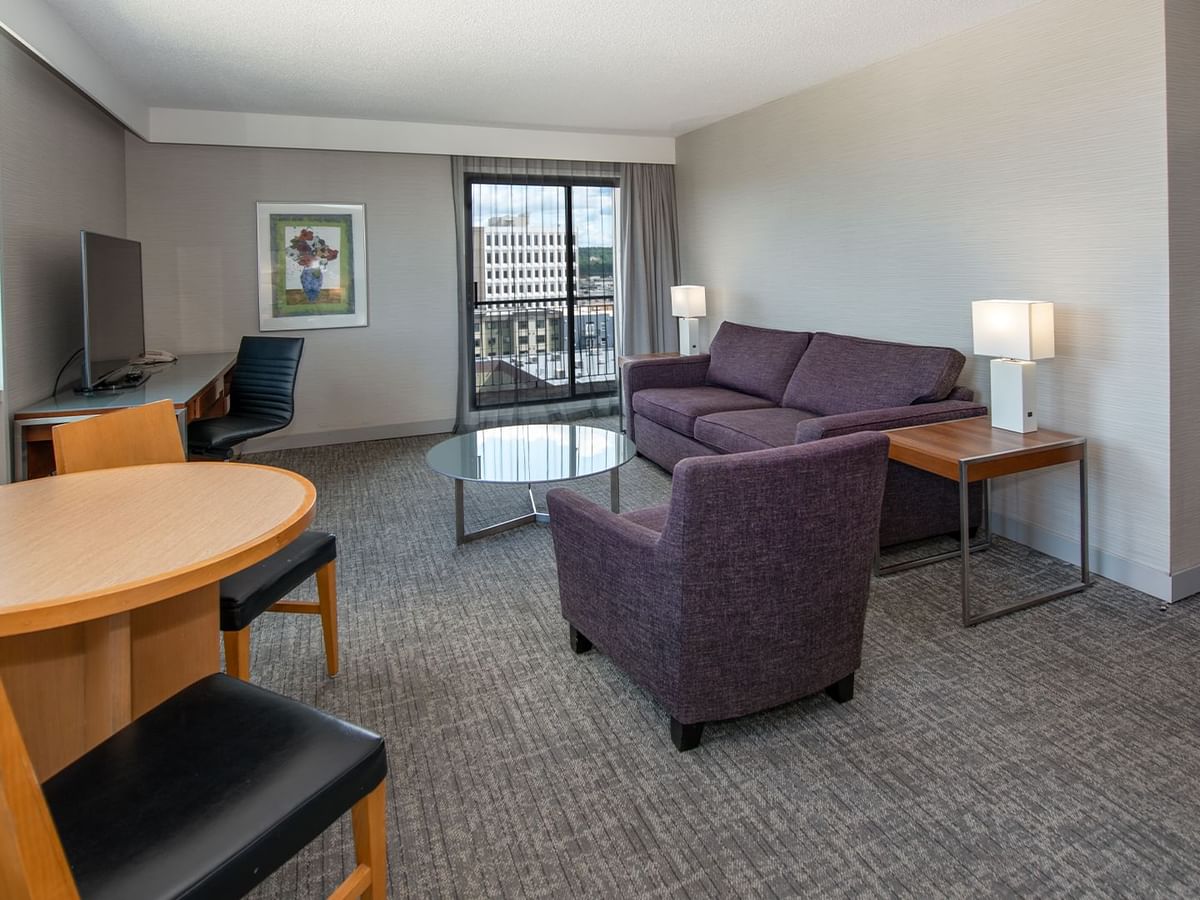 A hotel suite living room with sofa, table, and a TV
