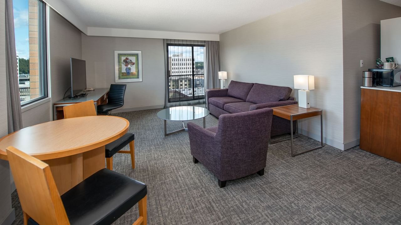 A hotel suite living room with sofa, table, and a TV