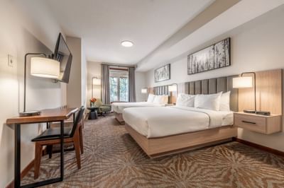 TV and work desk facing the beds in Deluxe Room with carpeted floors at Blackstone Mountain Lodge
