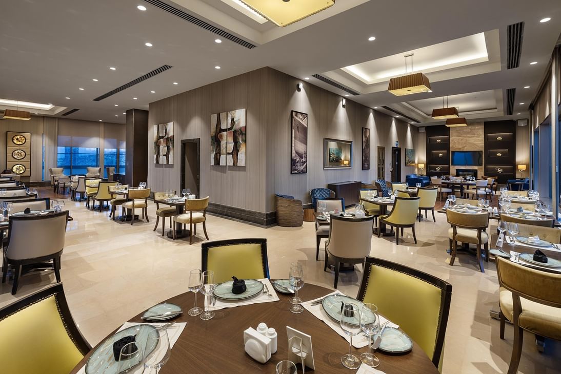 Yellow chairs with set tables under modern lights in Compass Restaurant at Titanic Business Kartal