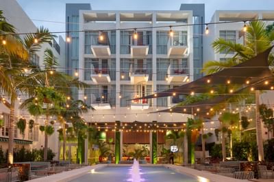 An outdoor pool with lights and palm trees in front of the Fairwind Hotel Miami