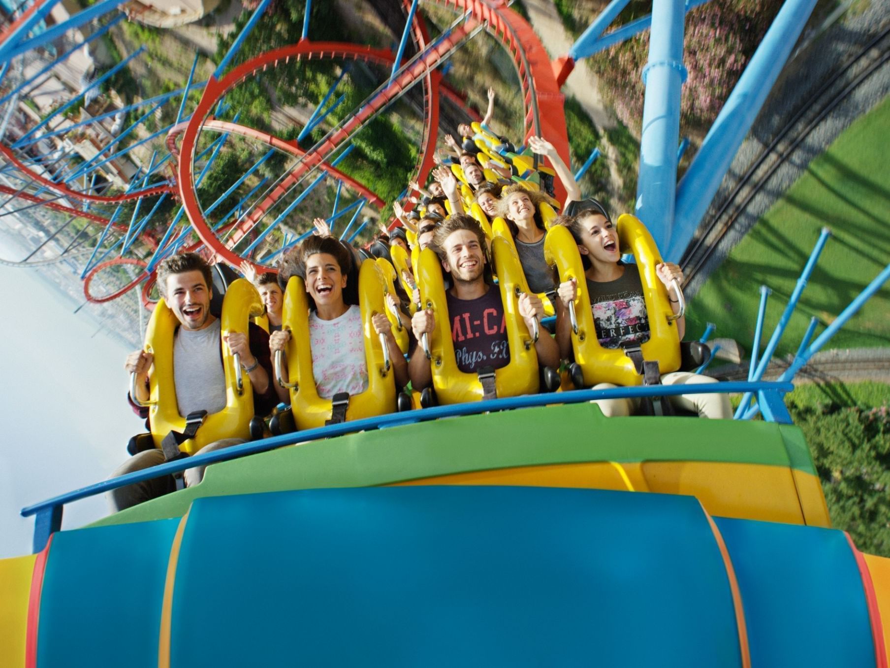 Group of people enjoying a thrilling roller coaster ride in PortAventura Park near Ponient Dorada Palace