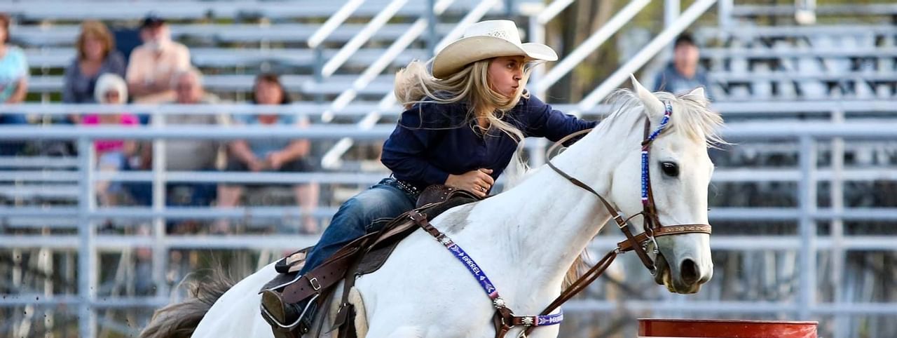 Woman in cowboy hat riding a horse during a show