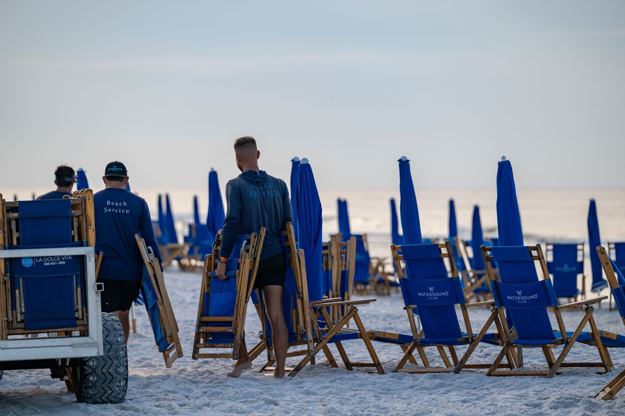 Watersound Beach Club beach service attendants setting up the beach chairs and umbrellas for Camp Creek inn guests to enjoy