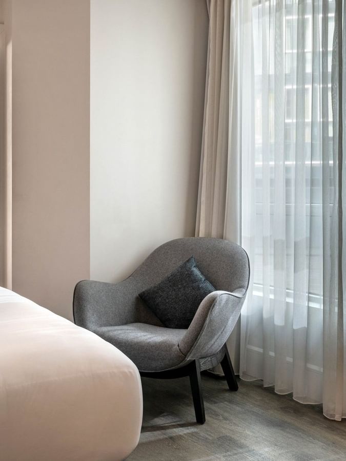 Chambre élégante avec un lit blanc et une chaise grise au Warwick Le Crystal – Montréal, à Montréal.