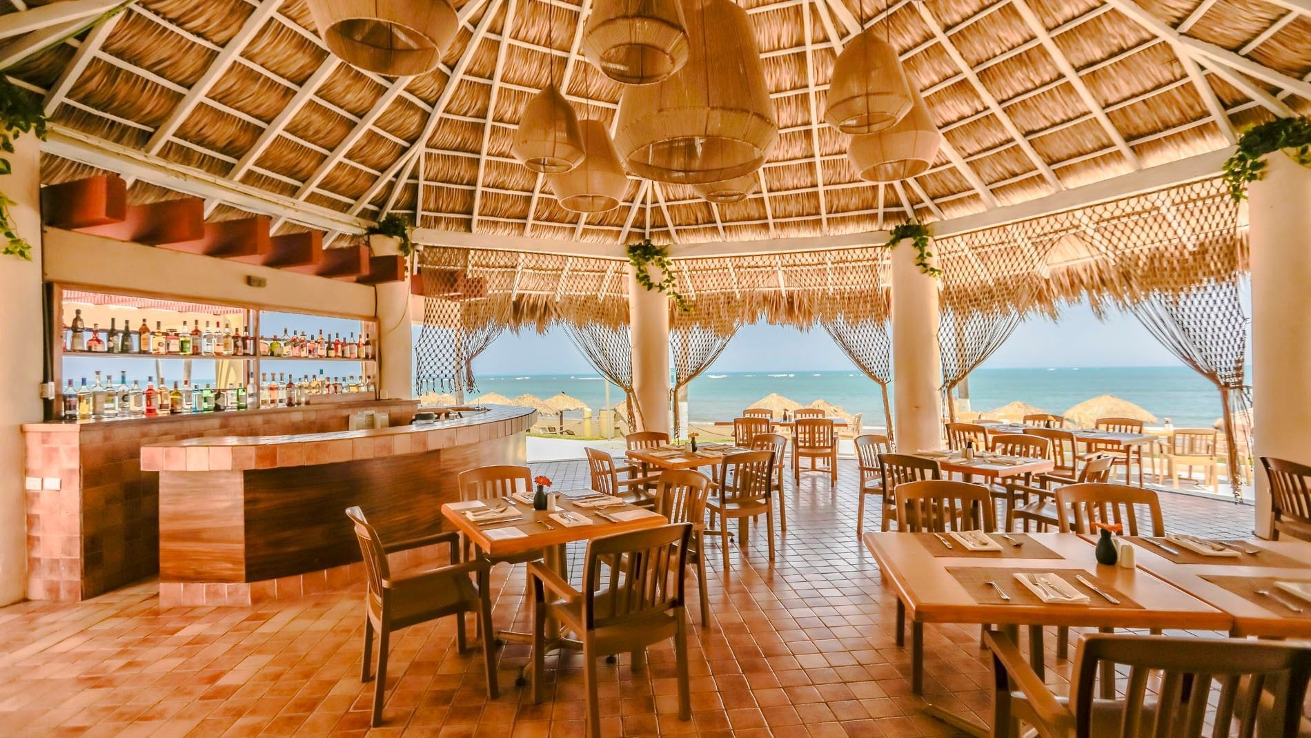 Tropical open-air La Vela restaurant featuring a curved counter, woven lanterns, and beach access at Camino Real Veracruz