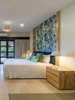 Large bed facing TV and leafy accent wall with light wood furniture in Lagoon Superior Room at warwick le lagon-vanuatu