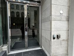 Entrance to ReStays Ottawa featuring glass doors, a disabled access button, and reflections of people standing outside