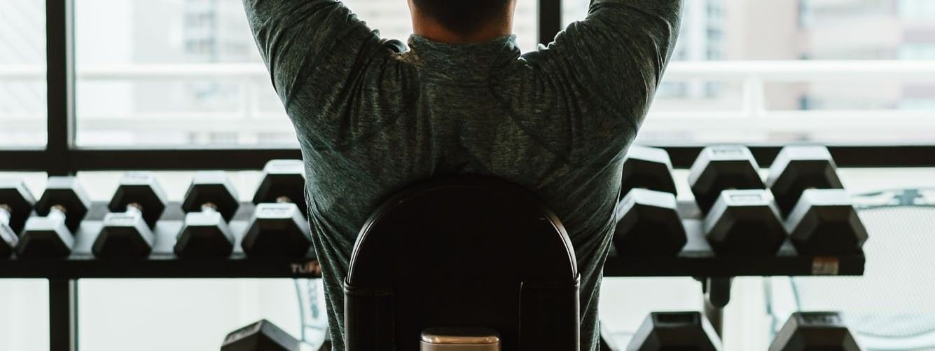 Man lifting dumbbells by a window with city views in the fitness center at Warwick Denver