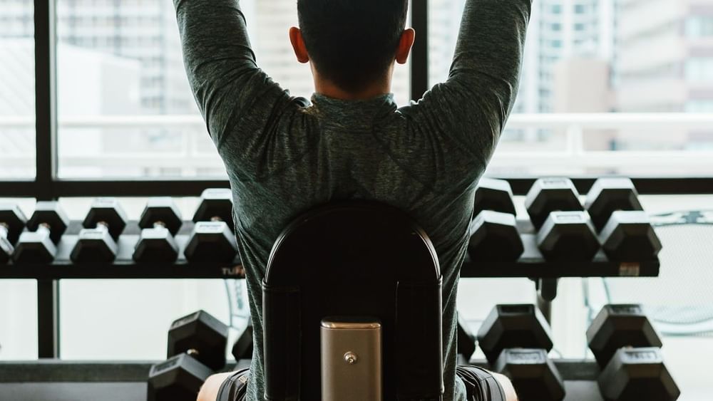 Man lifting dumbbells by a window with city views in the fitness center at Warwick Denver