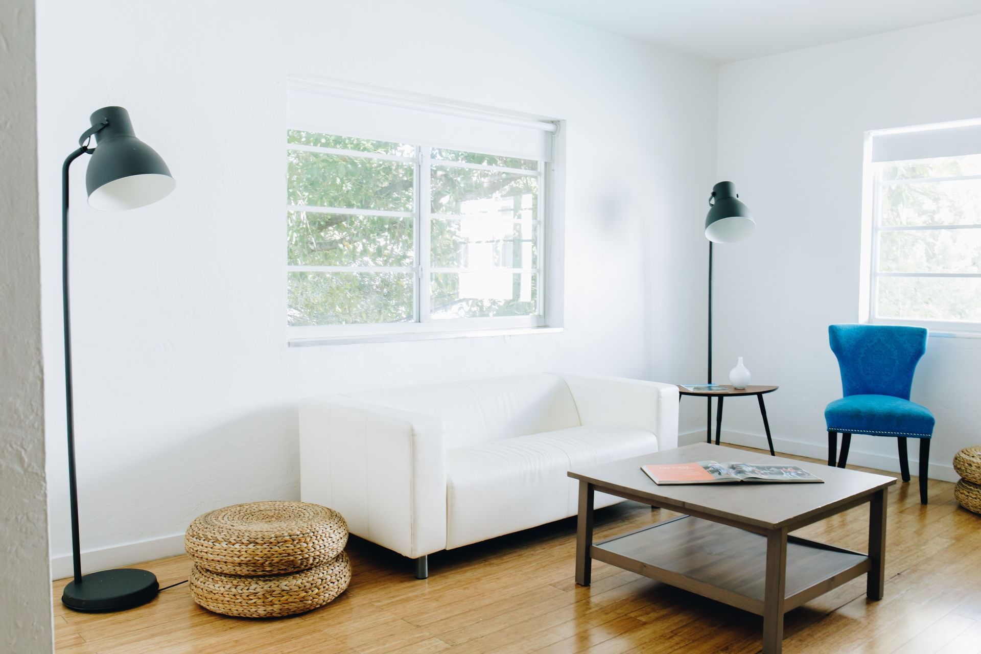 A brightly lit lobby area with a white couch, a coffee table, and a blue chair.