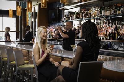 Woman holding a cocktail and talking with another woman in Harborside Bar and Lounge at Harborside Inn Boston