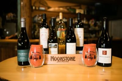 Bottles and glasses of wine from Moonstone Hotel Properties on a table in a bar.