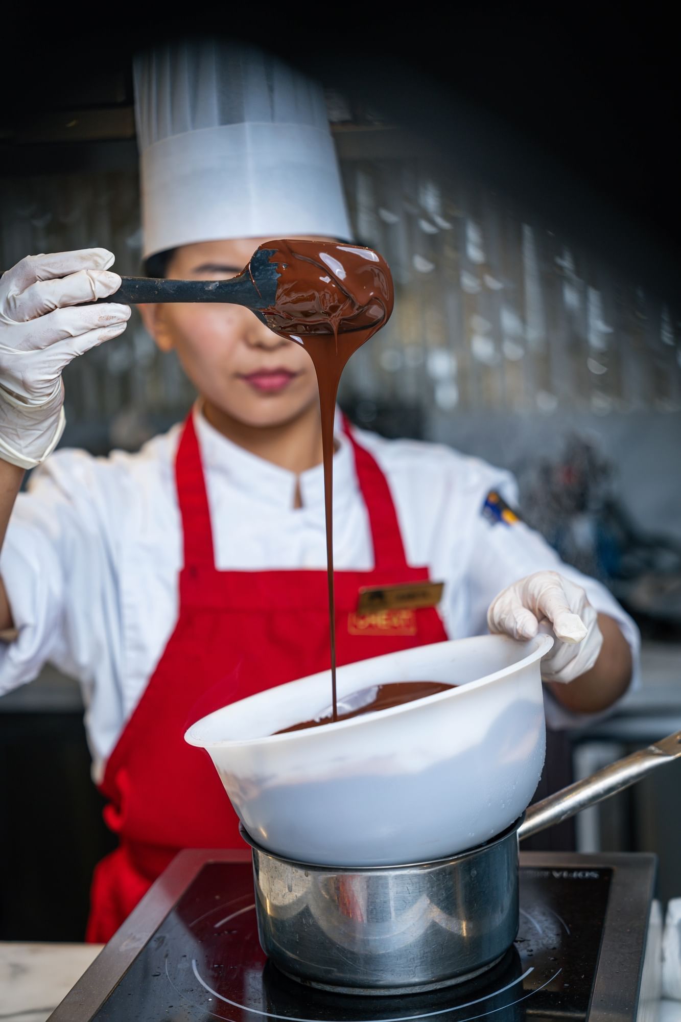 Chef with a ladle pouring rich, melted chocolate at Paramount Hotel Dubai, creating a beautiful and decadent stream