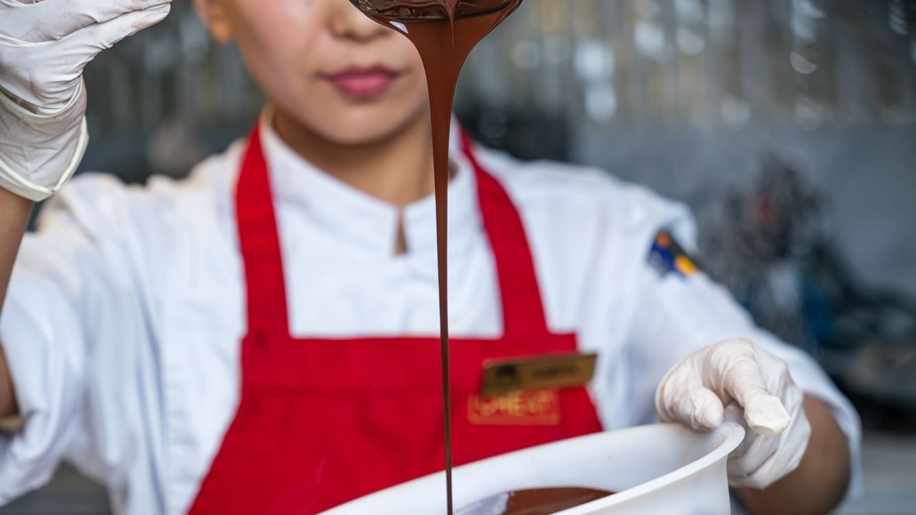 Chef with a ladle pouring rich, melted chocolate at Paramount Hotel Dubai, creating a beautiful and decadent stream