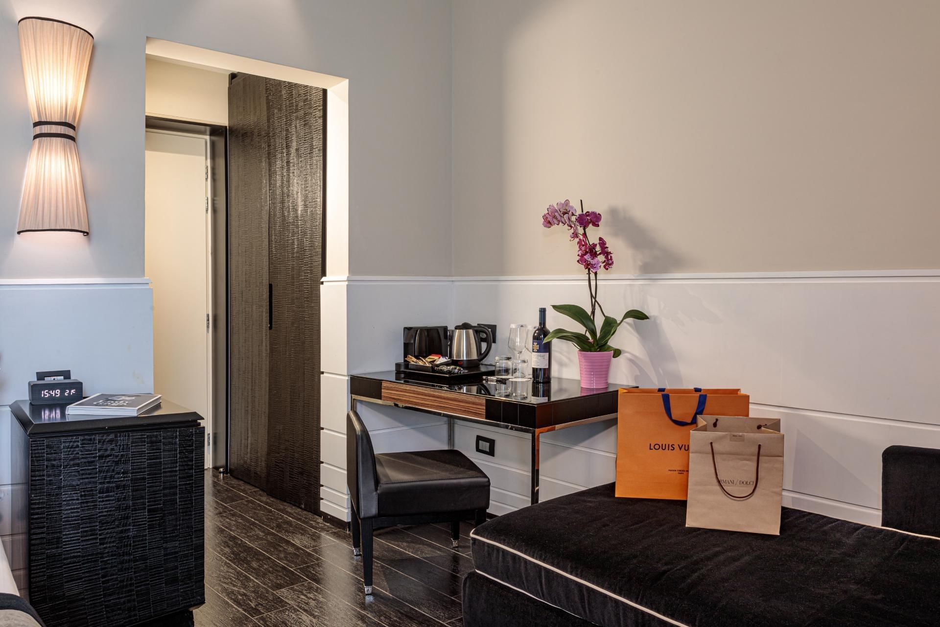 Stylish corner of the Deluxe Room at The Independent Suites with a chair, a table with drinks, and potted orchid