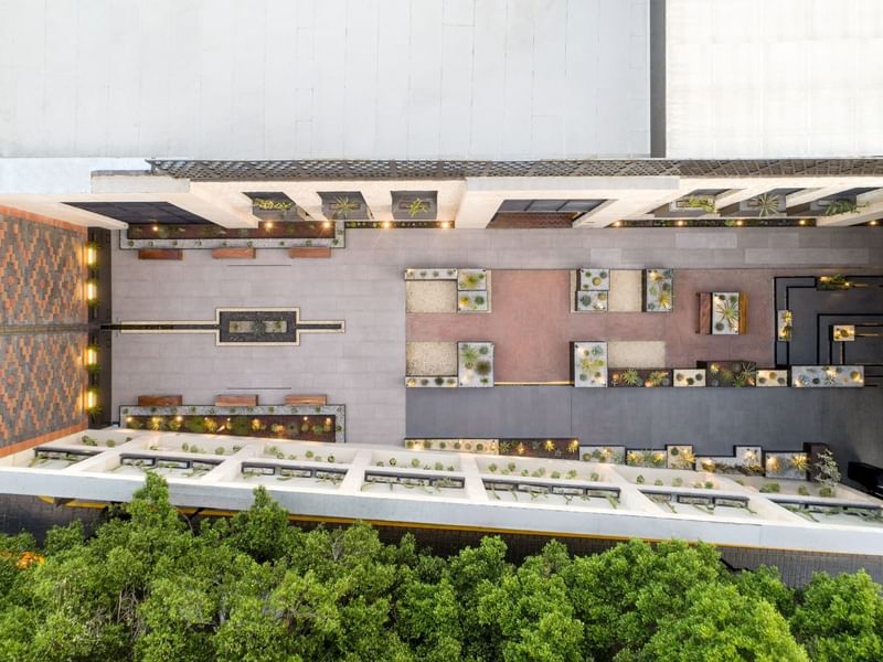 Aerial view of the hotel entrance with paved paths, lush greenery, and surrounding trees at Grand Fiesta Americana