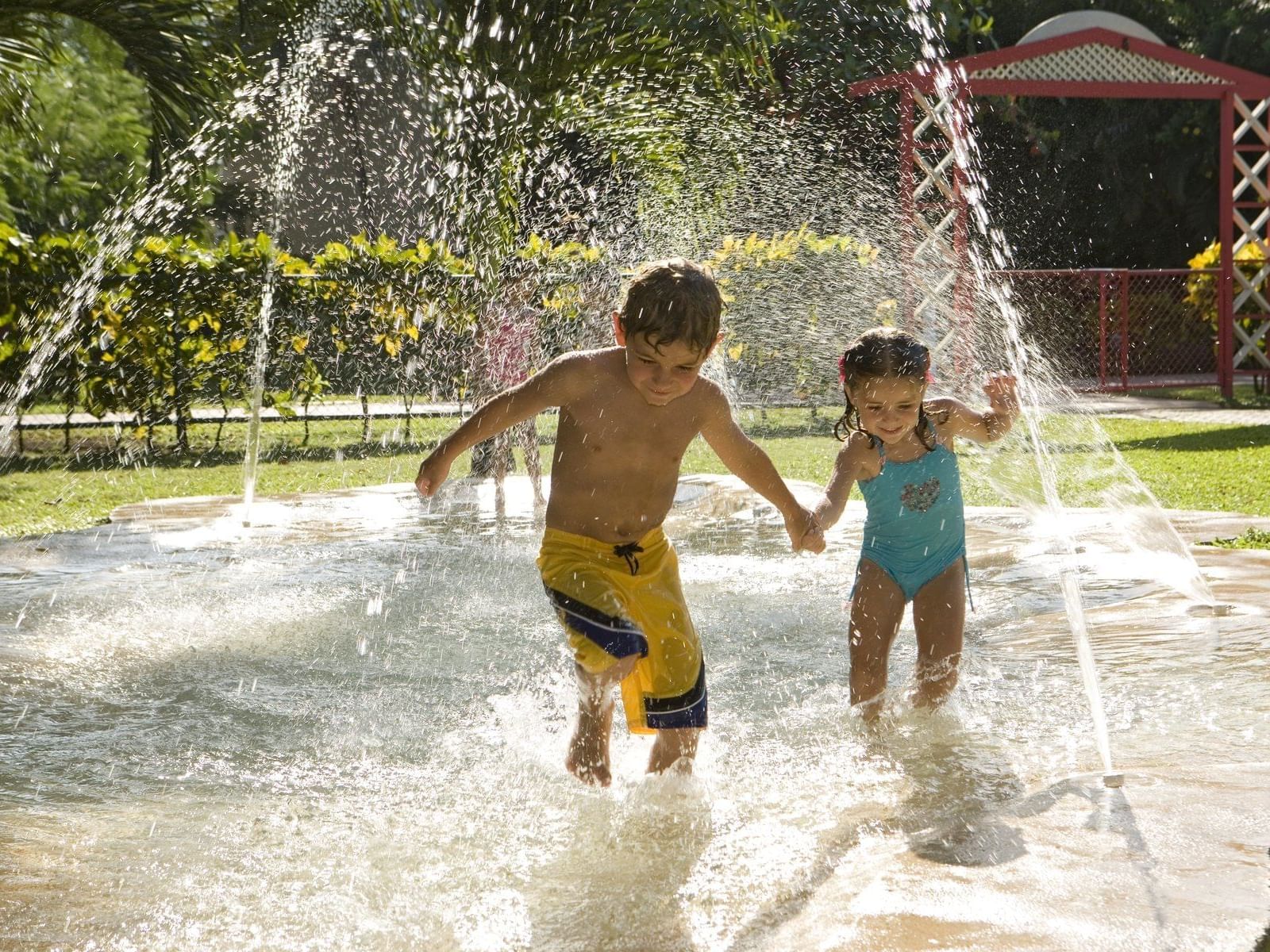 Two kids having fun at a water play fountain in Fiesta Resort