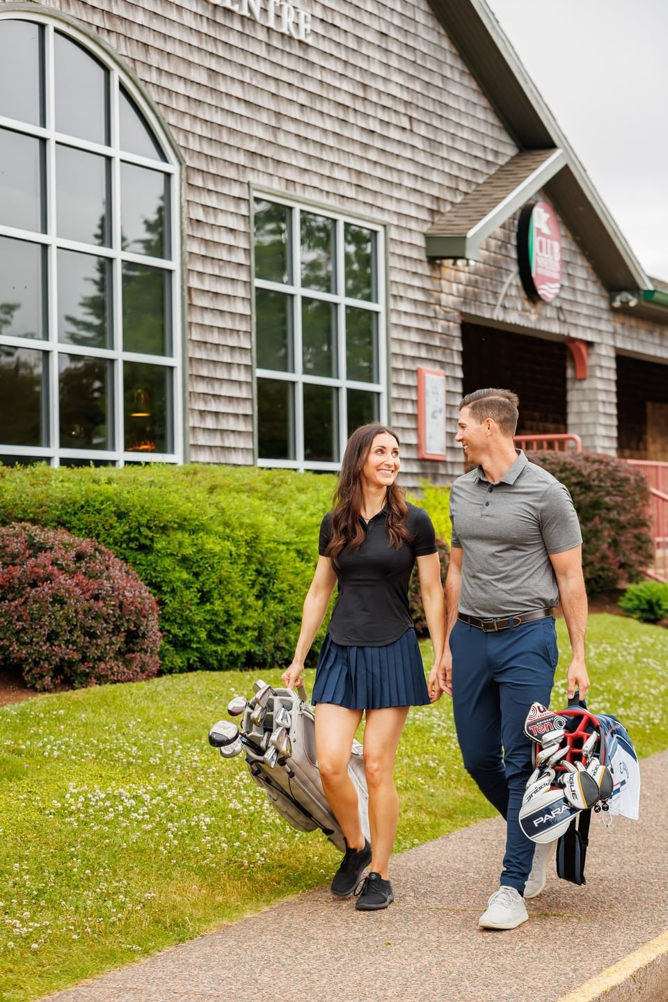 Couple with golf bags walking on a path at Rodd Brudenell River Resort, one of the premier places to stay in PEI
