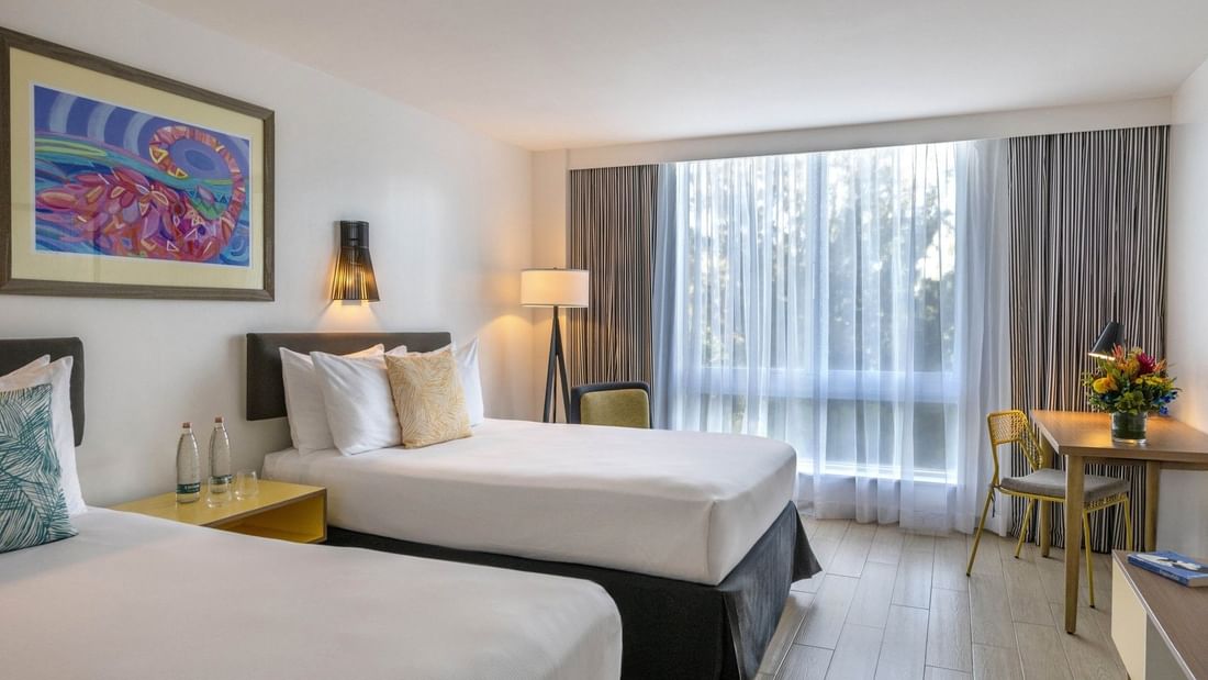 Twin beds by a wooden desk and chair under a floor in Island View at Warwick Paradise Island Bahamas